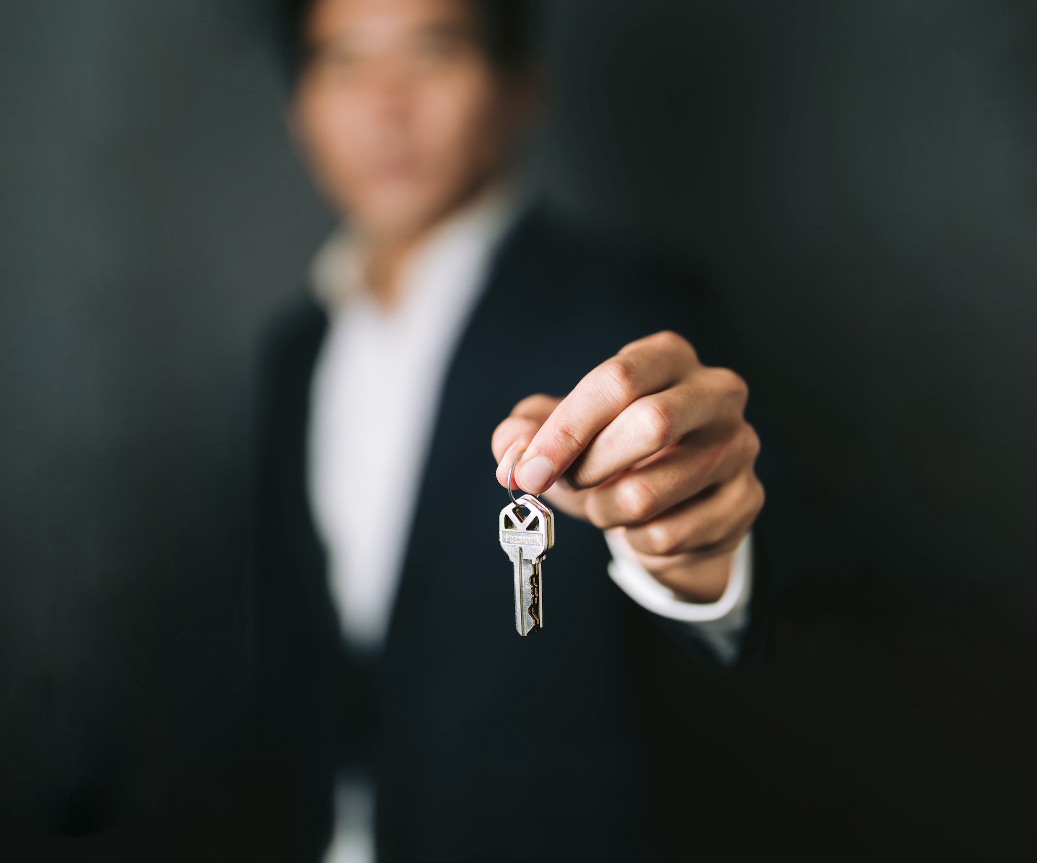 a realtor in a suit proudly displays a key, representing his personal brand and expertise in the real estate market.