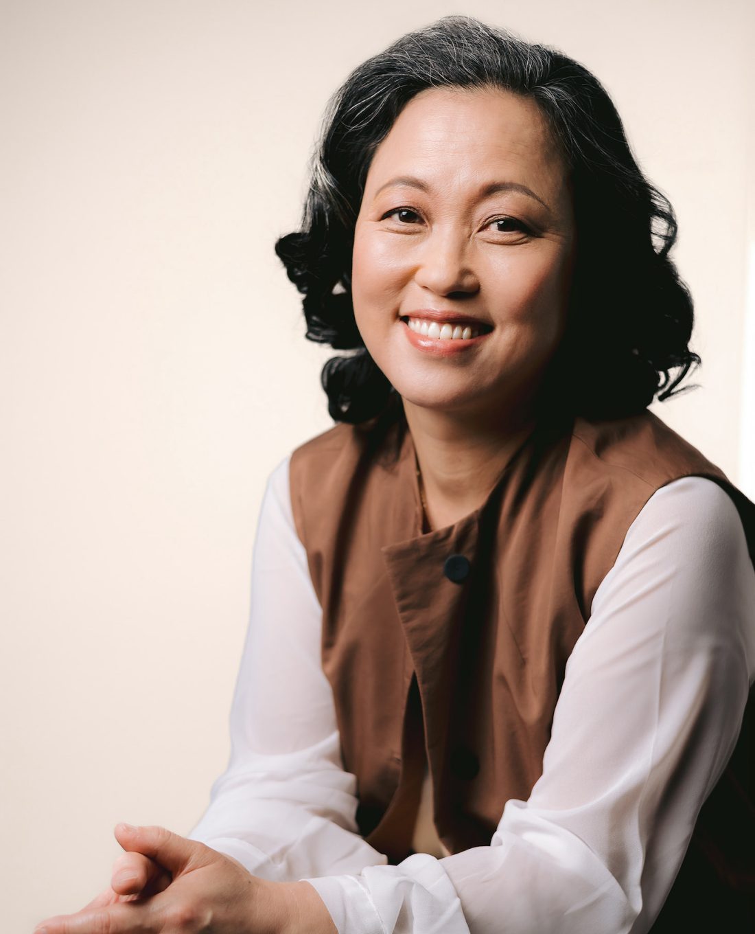 a businesswoman with dark hair and a brown shirt, captured in a professional branding session, highlighting her empathy and confidence.