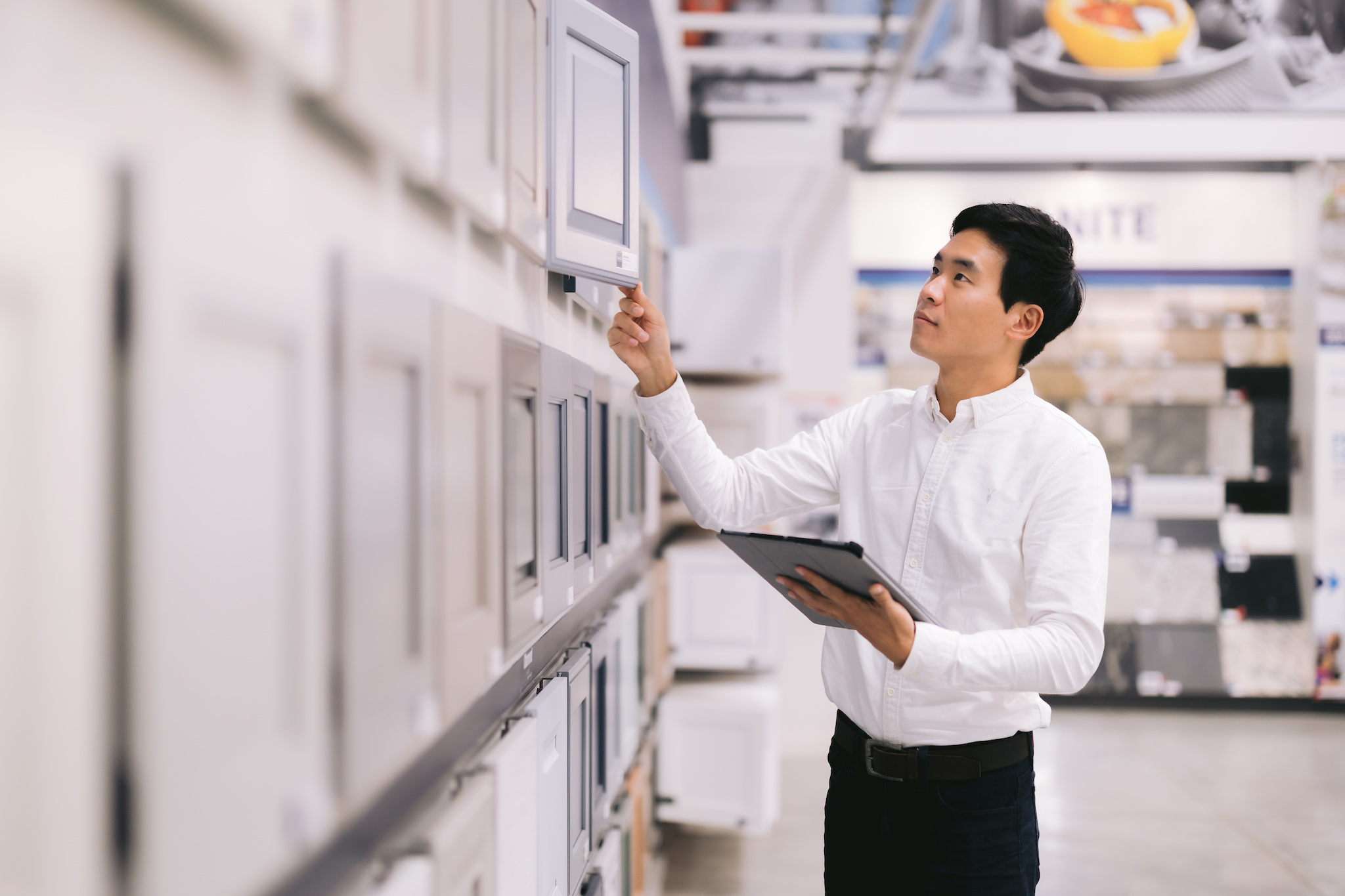 a male realtor examines cabinet door samples in a store during a personal branding photoshoot.