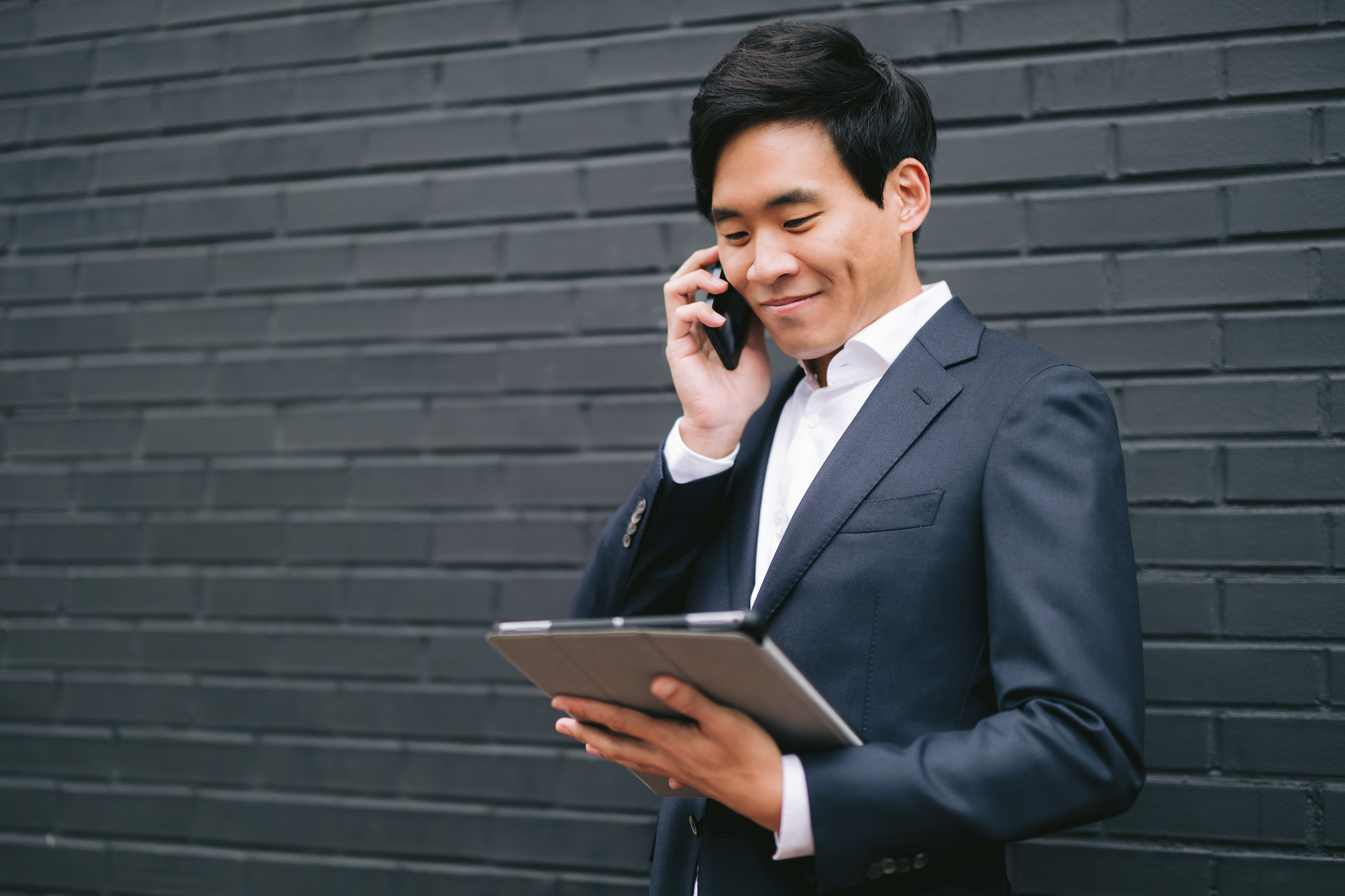 Atlanta male realtor holing a table and talking on a phone with a client.