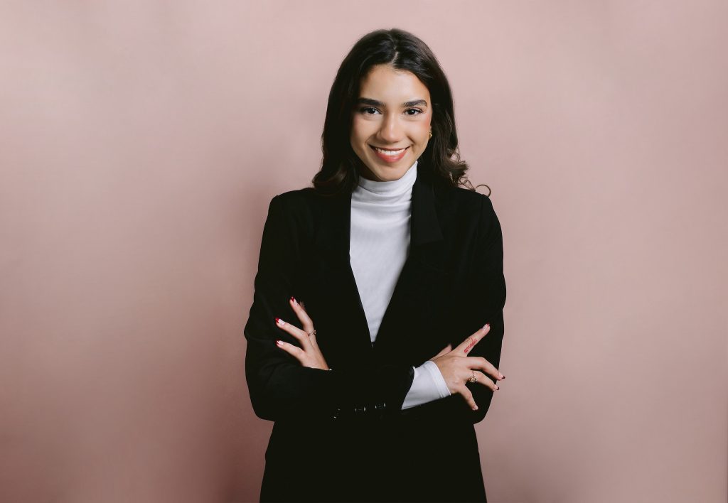 Portrait of a cheerful businesswoman on a pink backdrop, highlighting her personality during a professional photo session.